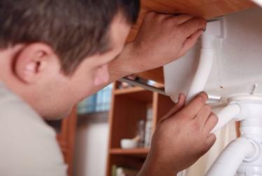 Broomfield plumbing professional reattaches a drain under a sink